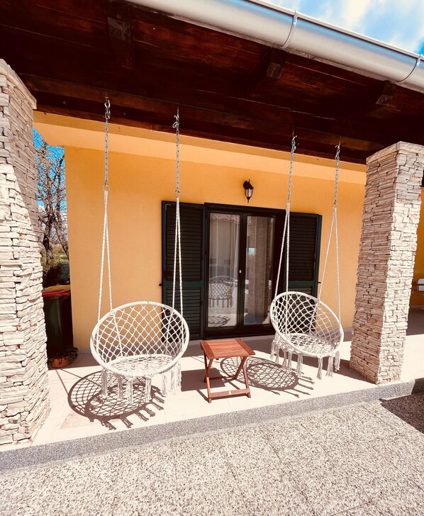 Une terrasse avec deux fauteuils à bascule en osier blanc et une petite table en bois.