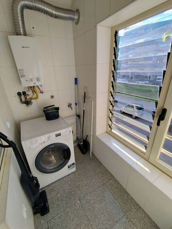 Laundry room with a washing machine and window offering a view of the surrounding area.