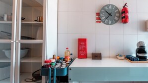 Eine Küche mit einer Uhr, einem Feuerlöscher und einer Kaffeemaschine.