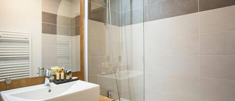 Une salle de bain moderne avec un grand lavabo blanc, une douche à parois de verre et un miroir au-dessus du lavabo.