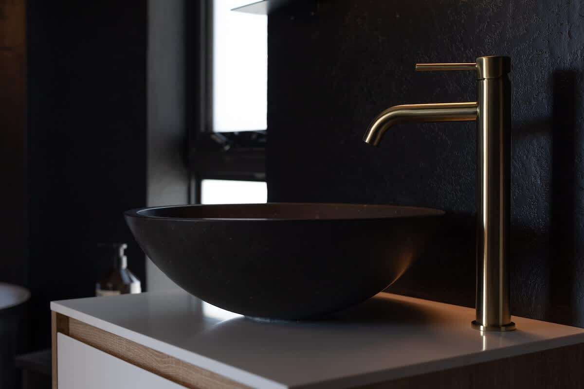 A modern bathroom with a dark-toned sink and a metallic faucet.