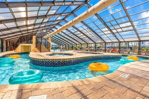 An indoor swimming pool with clear blue water, surrounded by a tiled deck and a glass roof structure. - Oceanfront Retreat with Resort Pools (Myrtle Beach)