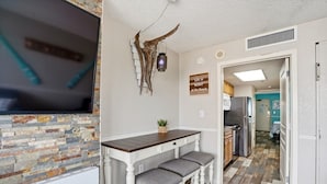 A kitchen with a stone backsplash, a wooden bar with two stools, a mounted deer head, and a kitchen island.