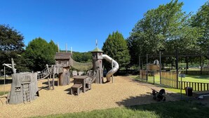 Une aire de jeux avec une structure d’escalade, des toboggans et une zone délimitée par une clôture.
