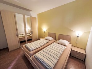 A twin room with two beds, a wardrobe, and bedside lamps.