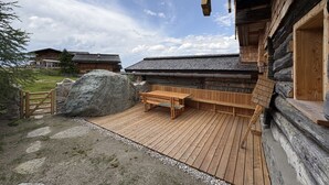A wooden cabin with a wooden deck and a bench. - Sennerin by Interhome (Forstau)
