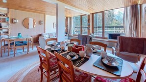 A spacious dining area with wooden furniture and large windows offering a view of the outdoors. - Résidence Les Tines by Interhome (Chamonix - Les Praz)