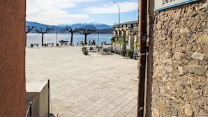 A stone building with a sign reading "pescatori" and a view of a lakeside area with benches and tables.