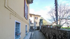 Un estrecho callejón con una pared de piedra a un lado y un edificio con ventanas y un balcón al otro.