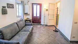 Un salón con un sofá gris, un radiador, una puerta y una lámpara.
