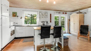 Eine moderne Küche mit weißen Schränken, einer Holz Arbeitsplatte und einem Essbereich mit zwei schwarzen Stühlen.