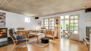 Ein geräumiges Wohnzimmer mit Holzboden, Kamin, einer Sofagarnitur, einem Couchtisch und einem Fernseher.