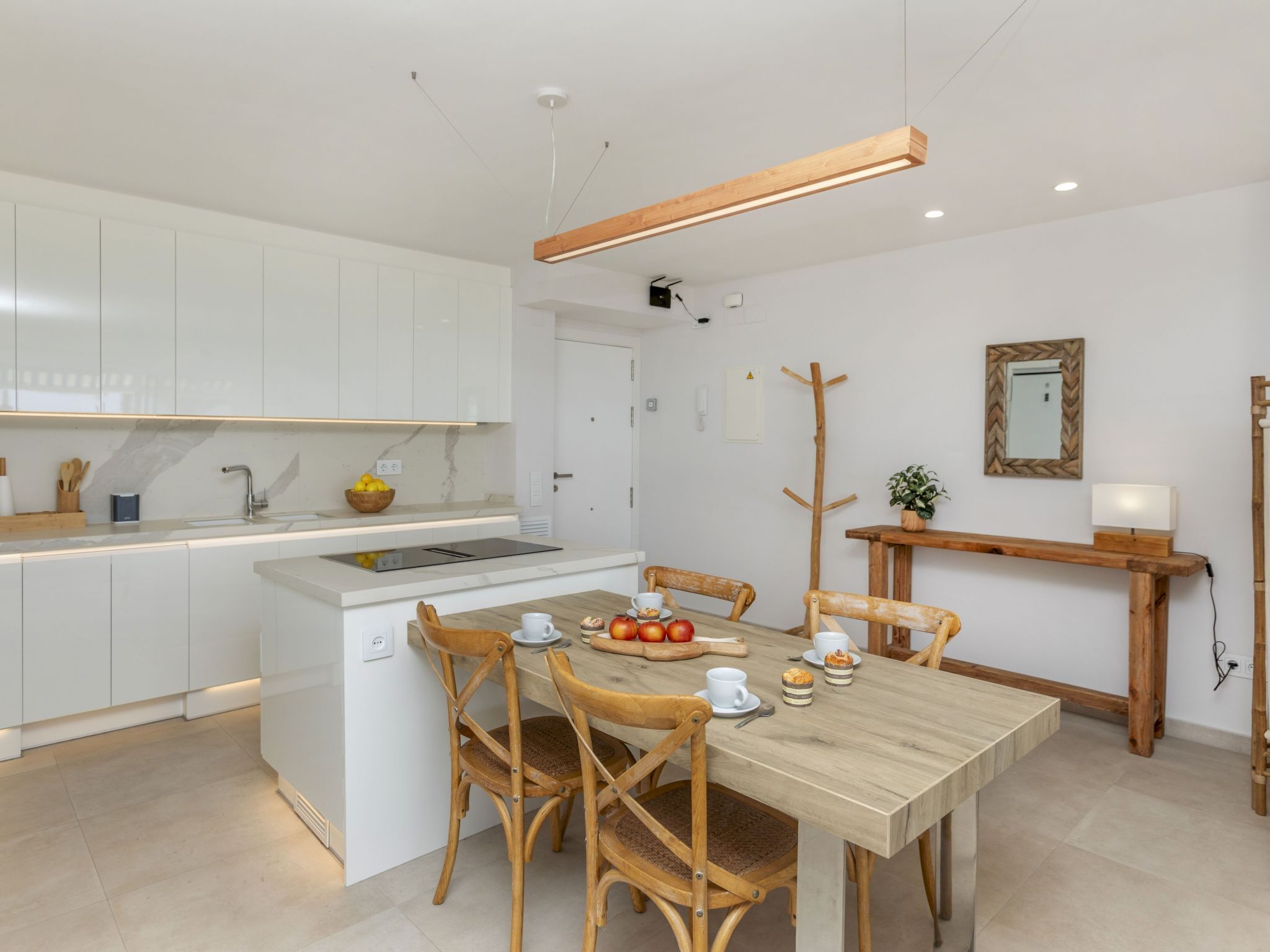 Une cuisine moderne avec des meubles blancs, une table à manger en bois et un buffet en bois.
