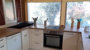 A compact kitchen with a built-in oven, a sink, and a window with a view of trees. - Ideal rental campsite oasis village 5⭐️ (Puget-sur-Argens)