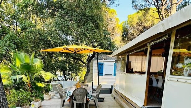A wooden deck with outdoor furniture, a covered seating area, and a large potted plant. - Ideal rental campsite oasis village 5⭐️ (Puget-sur-Argens)