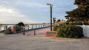 Un sendero pavimentado con un muro de ladrillo, una farola y una cerca de piquetes blancos.
