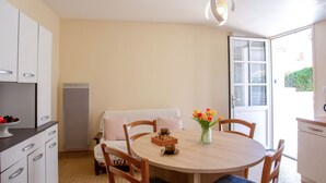 Una cocina compacta con armarios blancos, una mesa redonda de comedor y una pequeña mesa de centro.