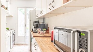 A modern kitchen with white cabinets, a wooden countertop, and a microwave.