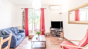 A living room with a blue sofa, a red chair, a coffee table, and a TV stand.