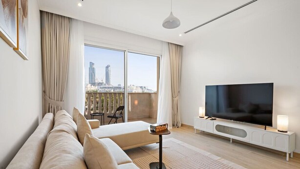 Et moderne hotelværelse med et stort vindue, et fladskærms-tv, en sofa og et lille bord.