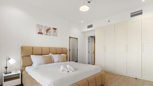 Et moderne soveværelse med en stor seng, et natbord med lampe og et garderobeskab.
