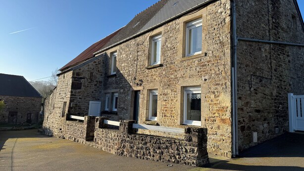 A stone building with multiple windows and a sloped roof.