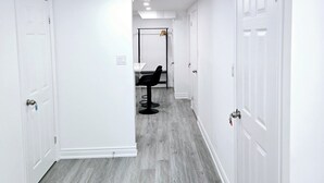 A hallway with white doors, a black chair, and a coat rack.