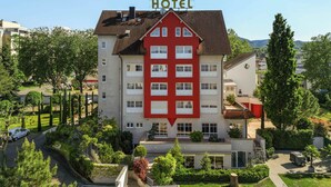 A hotel with a red and white facade, multiple windows, and a sign indicating its function.