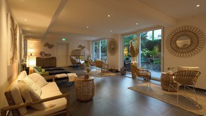 A spacious room with a sofa, chairs, a table, and a large window offering a view of the outdoors.