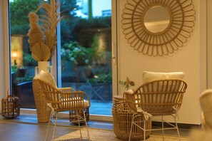 A room with wicker furniture, a large mirror, and a view of greenery outside. - Kirchers Park & Wellness Hotel Kaiserstuhl (Endingen am Kaiserstuhl)