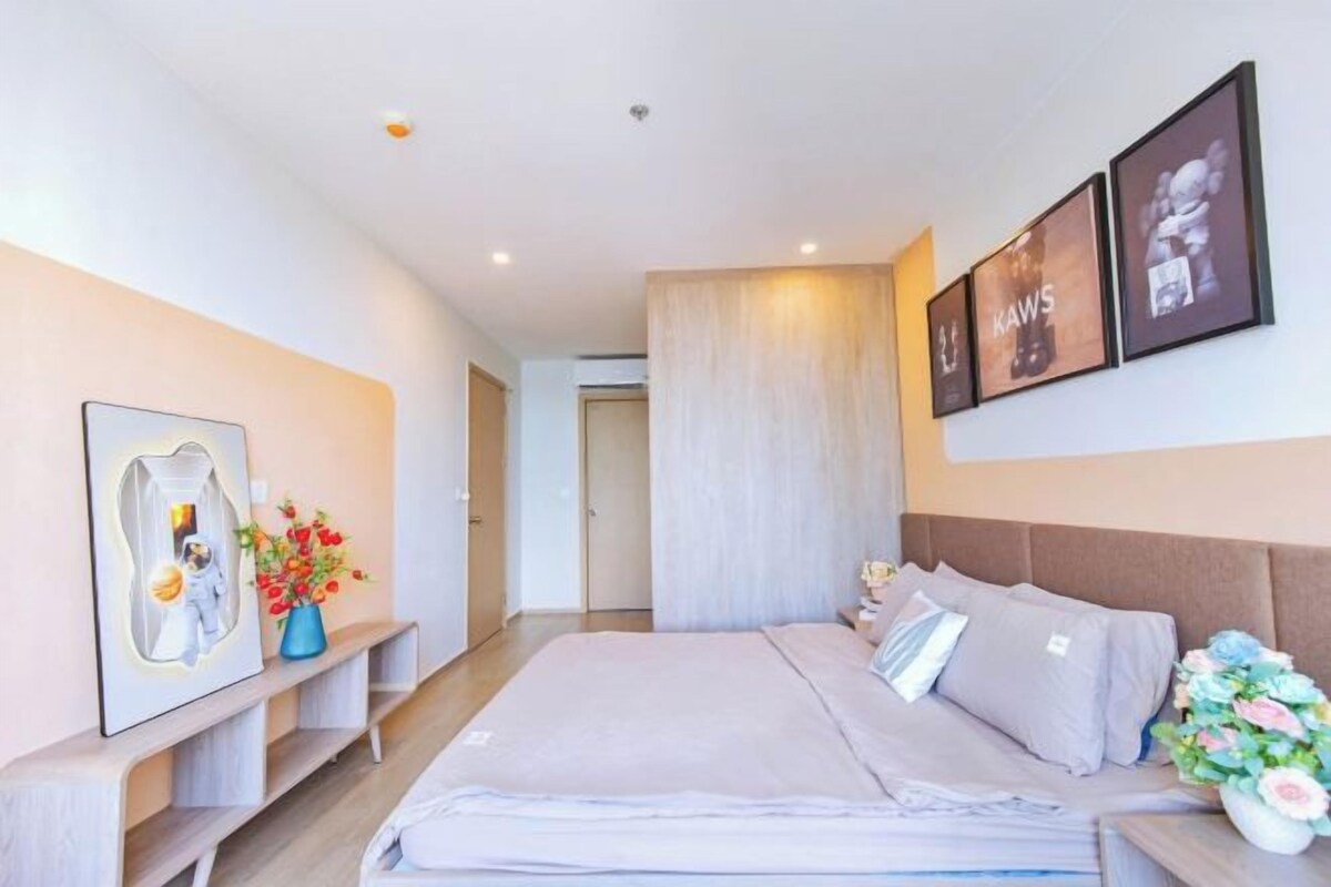 Una habitación de hotel moderna con una cama grande, una mesita de noche, un espejo y cuadros en la pared.