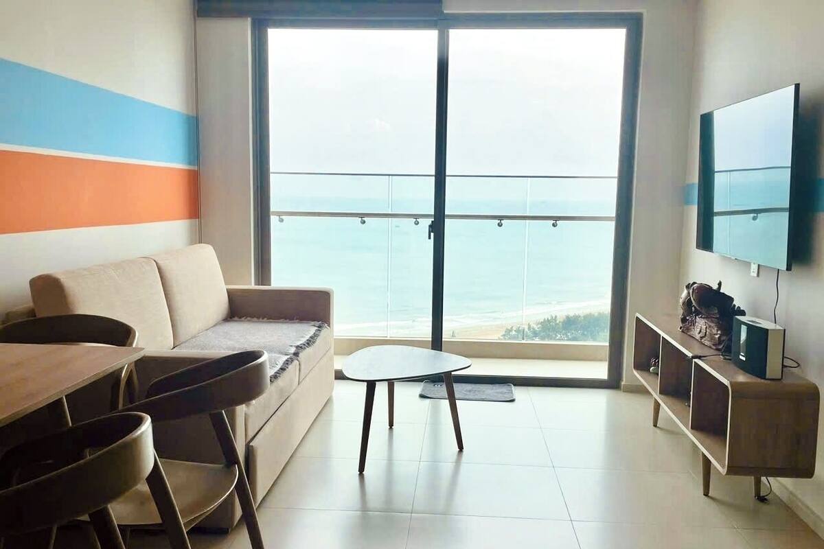 Un salon moderne avec un canapé, une petite table et un téléviseur fixé au mur.
