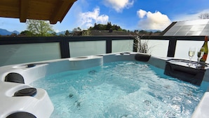 A hot tub with a view of mountains and a solar panel in the background. - Penthouse suite with romantic whirlpool in privacy. Ideal for couples (Rosenheim)