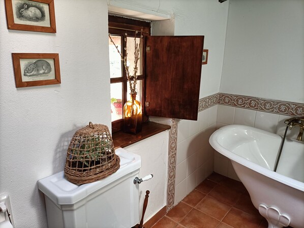 Une salle de bain comprenant des toilettes, un lavabo, une baignoire et des tableaux encadrés accrochés au mur.