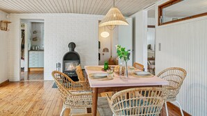 A dining area with a brick fireplace, wicker chairs, and a wooden ceiling.