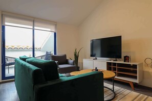 Relax in this stylish living room with a sofa, armchair, and flat-screen TV, offering a view of the outside.