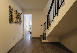 Staircase leads to an upper level in a spacious interior with a textured wall art piece.