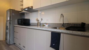 A modern kitchen with white cabinets, stainless steel appliances, and a granite countertop.