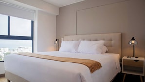 A modern bedroom with a large bed, two bedside tables, and a view of the city.