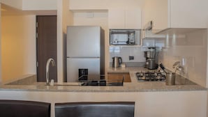 A modern kitchen with a built-in refrigerator, microwave, and gas stove. There is a sink with a faucet and a coffee maker on the counter.