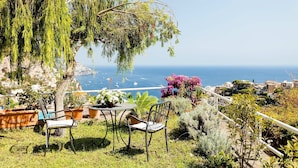 Un patio con mesa y sillas que ofrece vistas al mar.