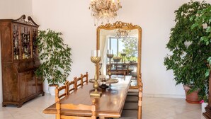 A dining room with a wooden table, chairs, a large mirror, and a chandelier. - Villa Lamaro with sea view - My Rental Homes (Sant'agnello)