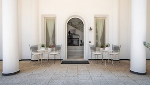 A covered outdoor area with two tables and chairs, a staircase leading to an upper level, and a wall-mounted light fixture. - Villa Lamaro with sea view - My Rental Homes (Sant'agnello)