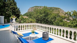 A rooftop terrace with lounge chairs, a small table, and a view of a mountain. - Villa Lamaro with sea view - My Rental Homes (Sant'agnello)