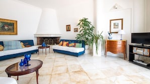 A living room with a fireplace, two sofas, a coffee table, a TV, and a plant. - Villa Lamaro with sea view - My Rental Homes (Sant'agnello)