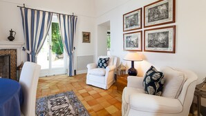 A living room with a sofa, armchairs, a patterned rug, and framed artwork on the wall.