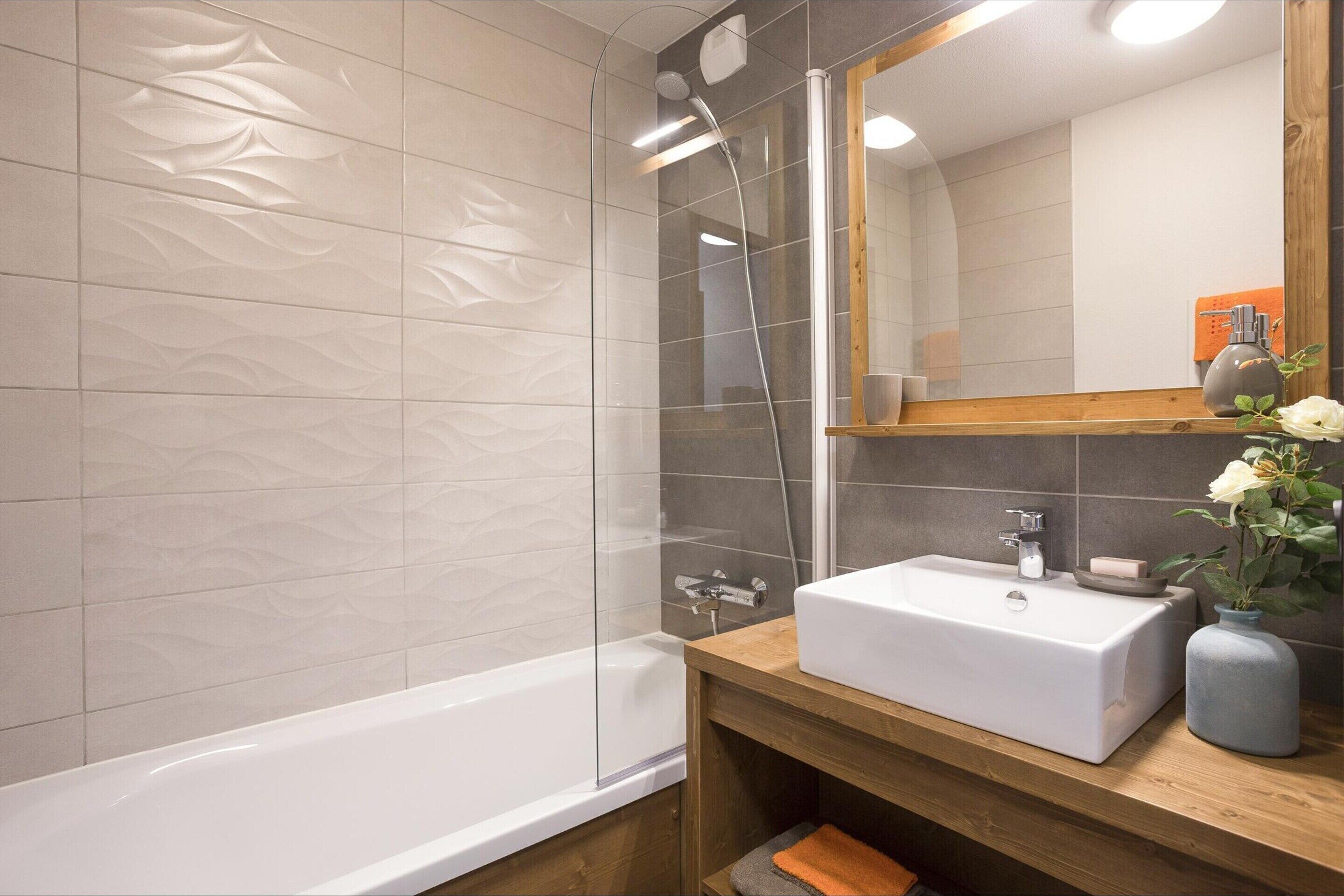 Un baño moderno con una bañera, un tocador de madera con un lavabo y un espejo.