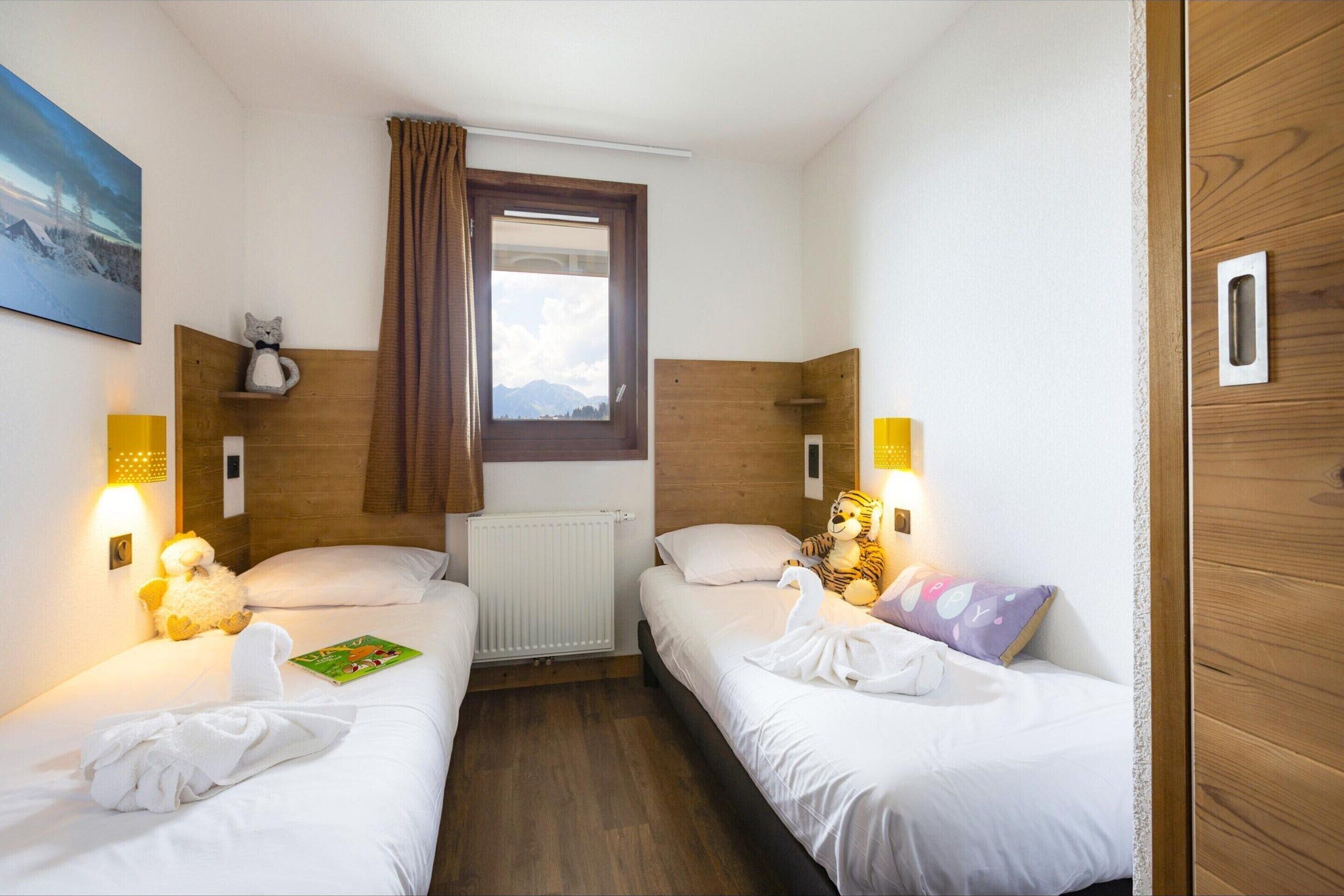 Camera d'albergo con due letti singoli, una finestra vista e un quadro appeso al muro, oltre a una testata del letto in legno.
