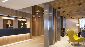 A reception area with a wooden reception desk, modern pendant lighting, and a fireplace. - Apartment in Hauteluce With Ski-in/ski-out Access (Hauteluce)