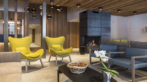 A modern living room with yellow armchairs, a grey sofa, a fireplace, and a black coffee table with a woven basket and white flowers. - Apartment in Hauteluce With Ski-in/ski-out Access (Hauteluce)